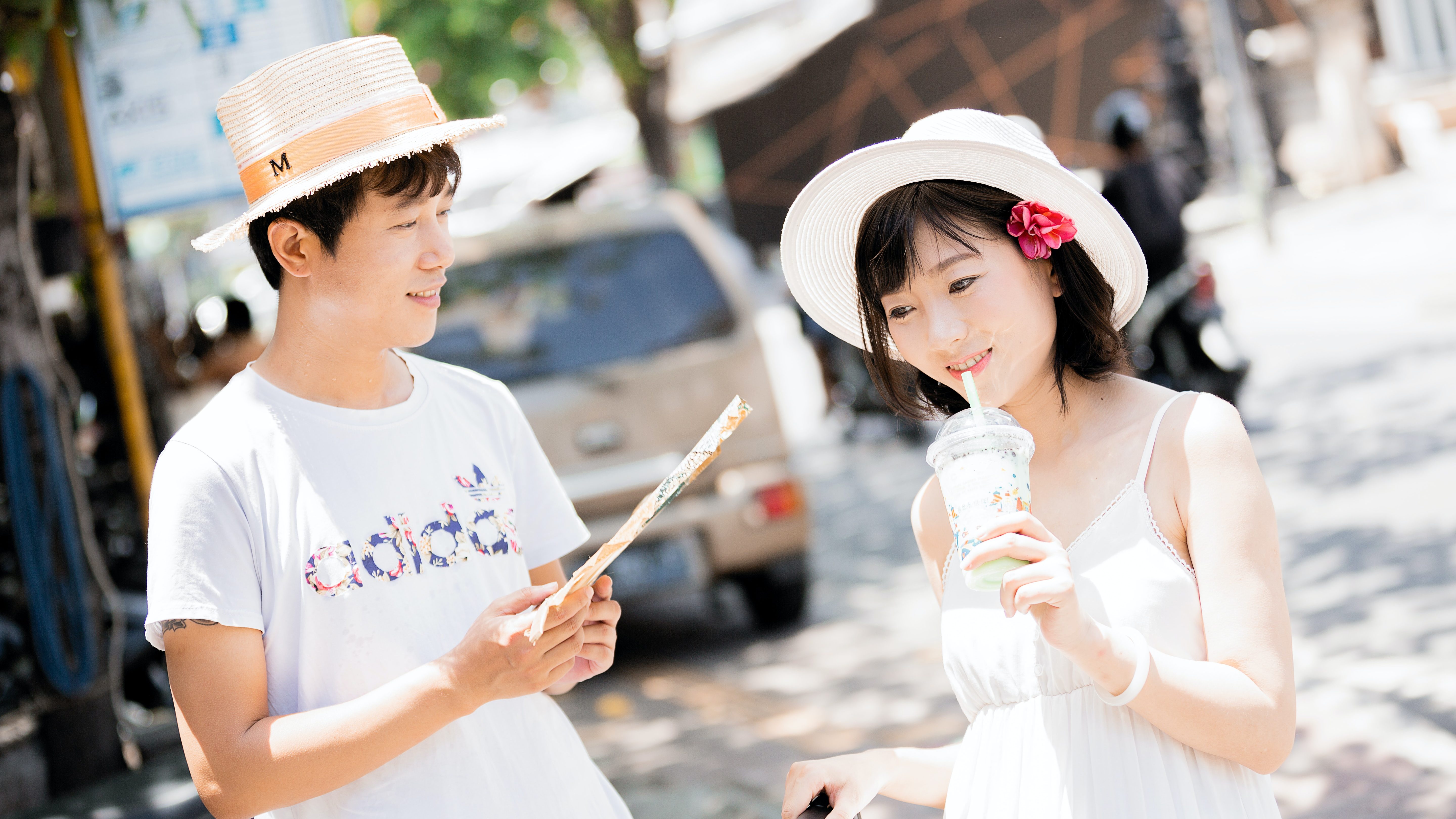 Un homme et une femme sont habillées en blanc avec chapeaux. Ils ont l'air de s'apprécier.