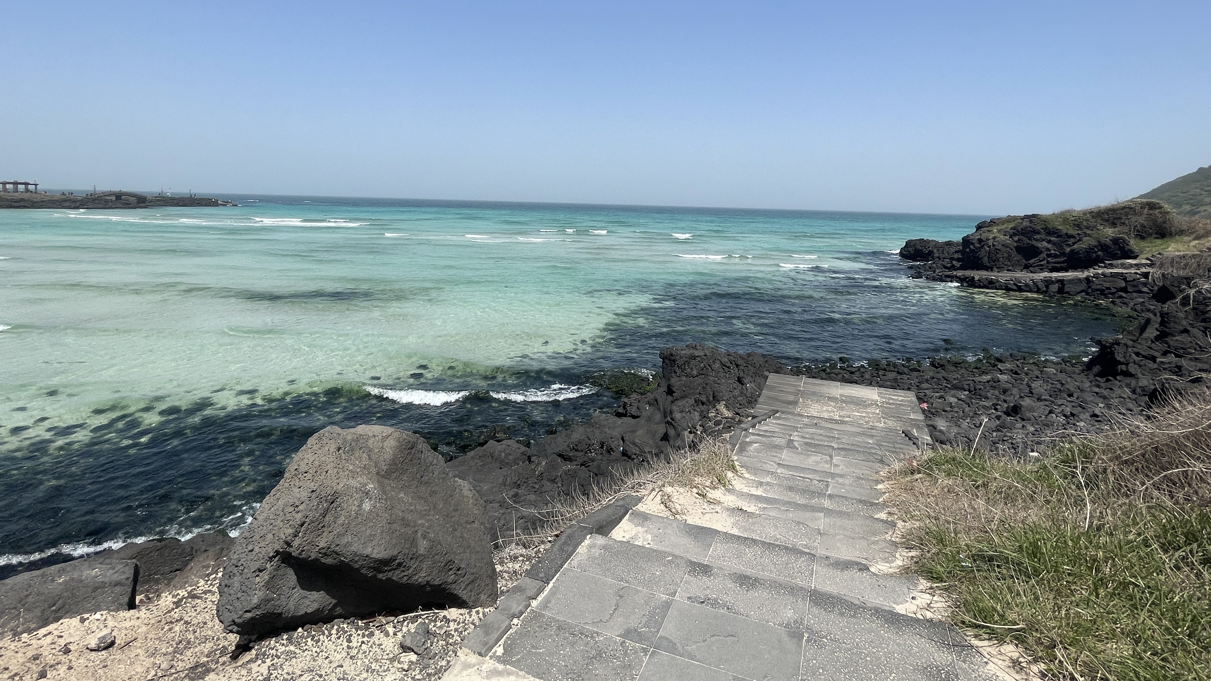 Des escaliers qui descendent sur une mer bleue turquoise en fond.